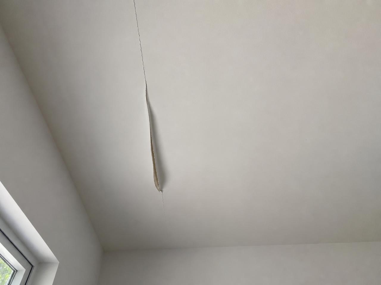White ceiling with a cracked, lifting drywall tape seam running across it.