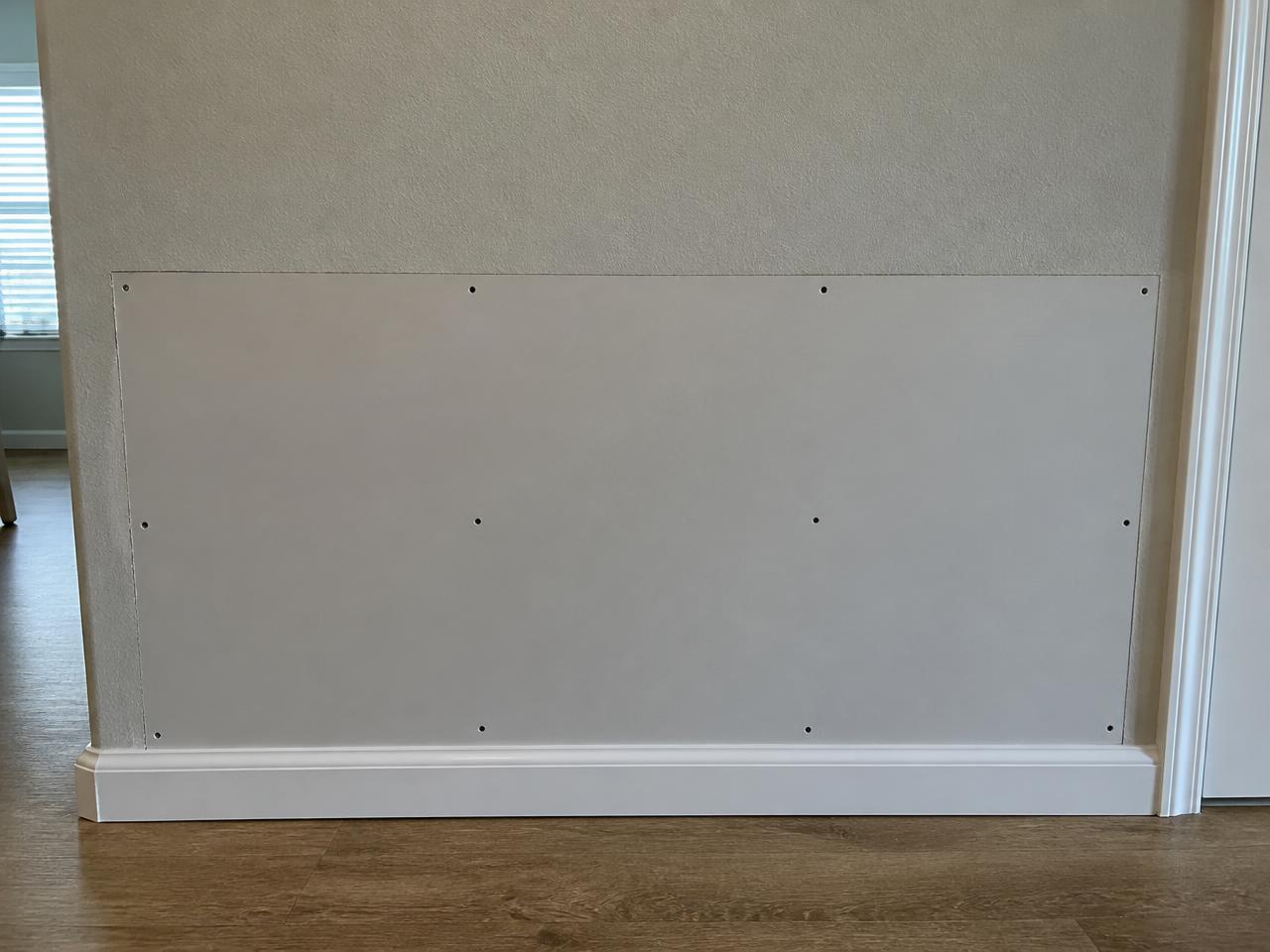 The same wall section after damaged drywall was cut out, replaced and finished paint-ready.